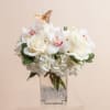 White floral arrangement in a clear square vase with a butterfly topper