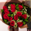Bouquet of red roses with white filler flowers in dark wrapping