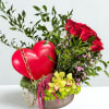 Red roses and orchids arranged with a heart decoration in a round box