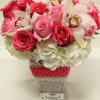 Pink roses and white orchids in a clear square vase