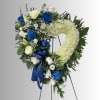 Heart-shaped floral wreath with white and blue roses on a stand