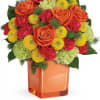 Orange roses with yellow and pink flowers in an orange glass vase