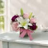 Pink and white flower arrangement in a glass vase with a gingham ribbon