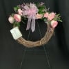 Pink rose wreath with a large ribbon bow on a grapevine frame
