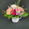 Pink and white flower arrangement in a decorative mug