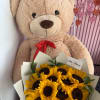 Teddy bear holding a bouquet of sunflowers with a red ribbon