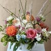 Mixed bouquet of roses, hydrangeas, and white blooms in a white vase