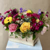 Mixed bouquet of roses, gerbera daisies, and purple blooms in a wooden box