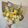 Hand-tied bouquet of yellow and white flowers wrapped in brown paper
