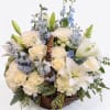Basket arrangement of white lilies, roses, and blue flowers
