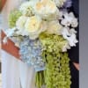 Wedding bouquet of white and pale blue flowers with trailing green blooms