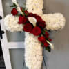 Cross-shaped floral tribute with white chrysanthemums, red roses, and white calla lilies