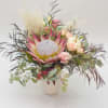 Mixed bouquet with a large pink protea in a white vase