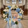 Floral wreath with blue ribbon and teddy bear in a church setting