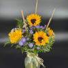 Sunflowers and purple daisies in a glass vase with raffia tie