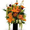 Orange lilies and mixed flowers arranged in a tall black vase