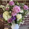 Pink roses and peonies in a white vase with white and purple flowers