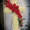 A 30" cross covered in white cushion pompons and a spray of