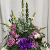 Purple and white floral arrangement in a clear cross vase with a purple ribbon
