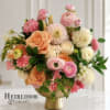 Pink, peach, and white flowers arranged in a gold pedestal vase