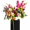 Bright mixed flower arrangement in a white vase on a black pedestal