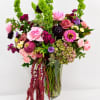 Mixed pink and purple flower arrangement in a glass vase