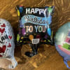 Three birthday foil balloons on a wooden table