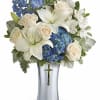 White lilies, cream roses, and blue hydrangeas in a silver vase