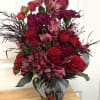 Bouquet of red roses, pink alstroemeria, and dark carnations in a decorative vase