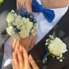 White rose wrist corsage and matching boutonniere with blue ribbon on a couple in formalwear