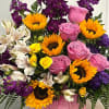 Pink roses, sunflowers, and purple flowers arranged in a pink box