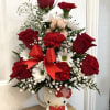 Red roses and white daisies arranged in a Hello Kitty mug with a red bow.