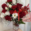 Red roses and white daisies in a Hello Kitty tumbler with a red bow.