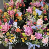 Assorted pink and orange floral arrangements with lilies and roses in vases