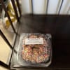 Plastic clamshell container of sprinkle-covered cookies on a chair