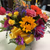 Colorful mixed bouquet with sunflowers, roses, and daisies in a glass vase