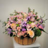Large pastel flower arrangement in a wooden basket