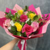 Bouquet of pink and yellow roses wrapped in bright pink paper