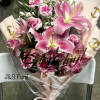 Pink lilies and carnations in a wrapped bouquet with a birthday topper