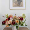 Mixed floral arrangement in a white vase on a wooden table