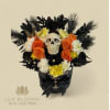 Black floral arrangement with a skull centerpiece and orange, white, and yellow flowers