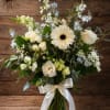 White and pale blue floral bouquet in a glass vase with a satin ribbon