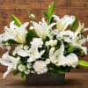 White lilies and small white flowers arranged in a rectangular container