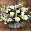 White and pale yellow flower arrangement in a white wicker basket
