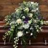 White and purple floral spray arranged on a casket