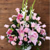 Pink lilies and roses arranged in a white vase