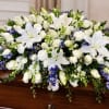 White and blue floral spray on a wooden casket