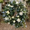 White roses and pale blue flowers arranged on a metal stand