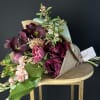 Bouquet of deep burgundy and pink flowers wrapped in kraft paper