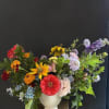 Colorful mixed bouquet in a white vase with zinnias and daisies